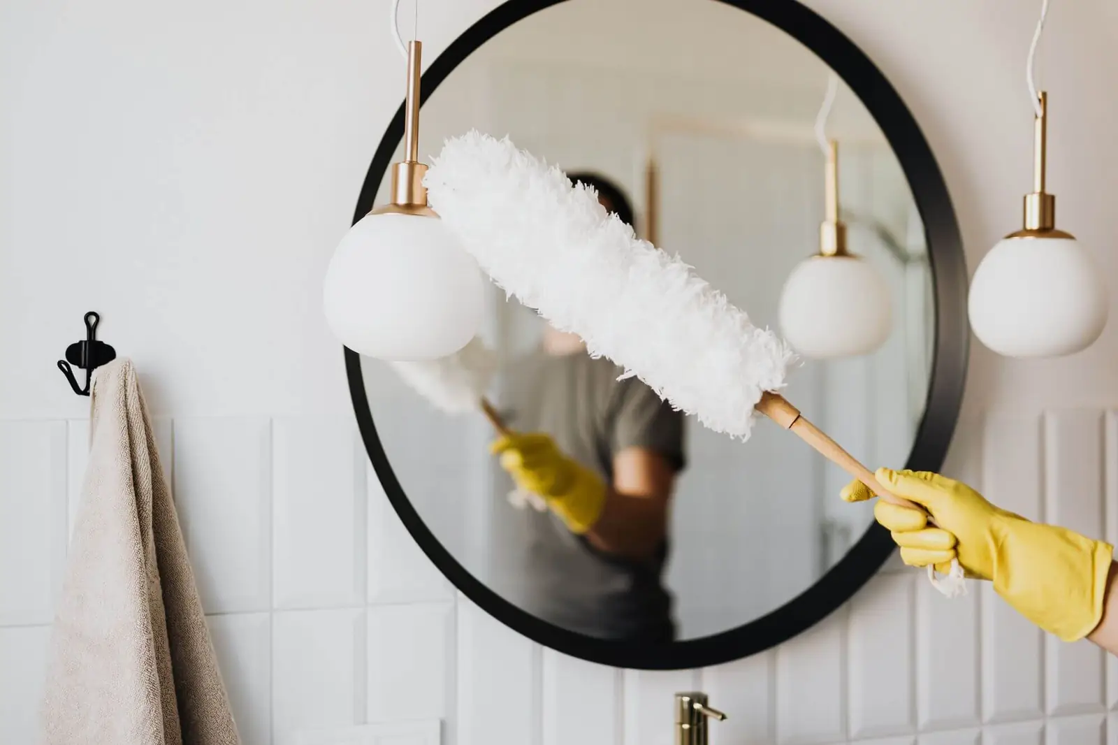 Dusting a round mirror with a duster